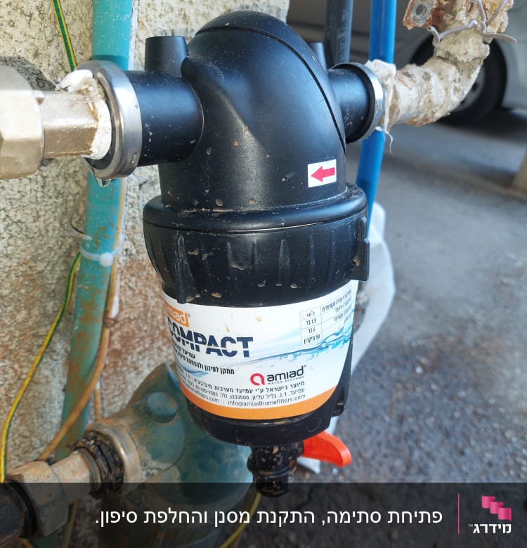 מסנן מים שחור מחובר לצינורות עם ברז אדום